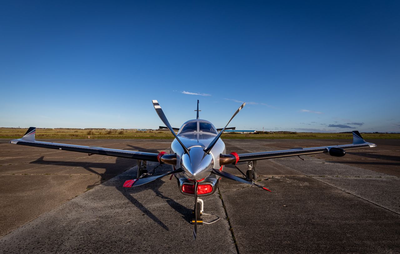A front view of an executive turboprop on a parking apron, with a four-bladed propeller